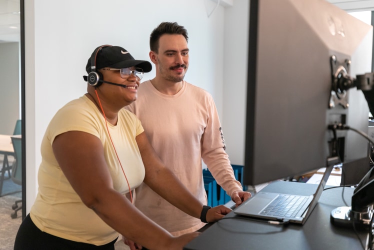 Two people working in a stand up table with a laptop